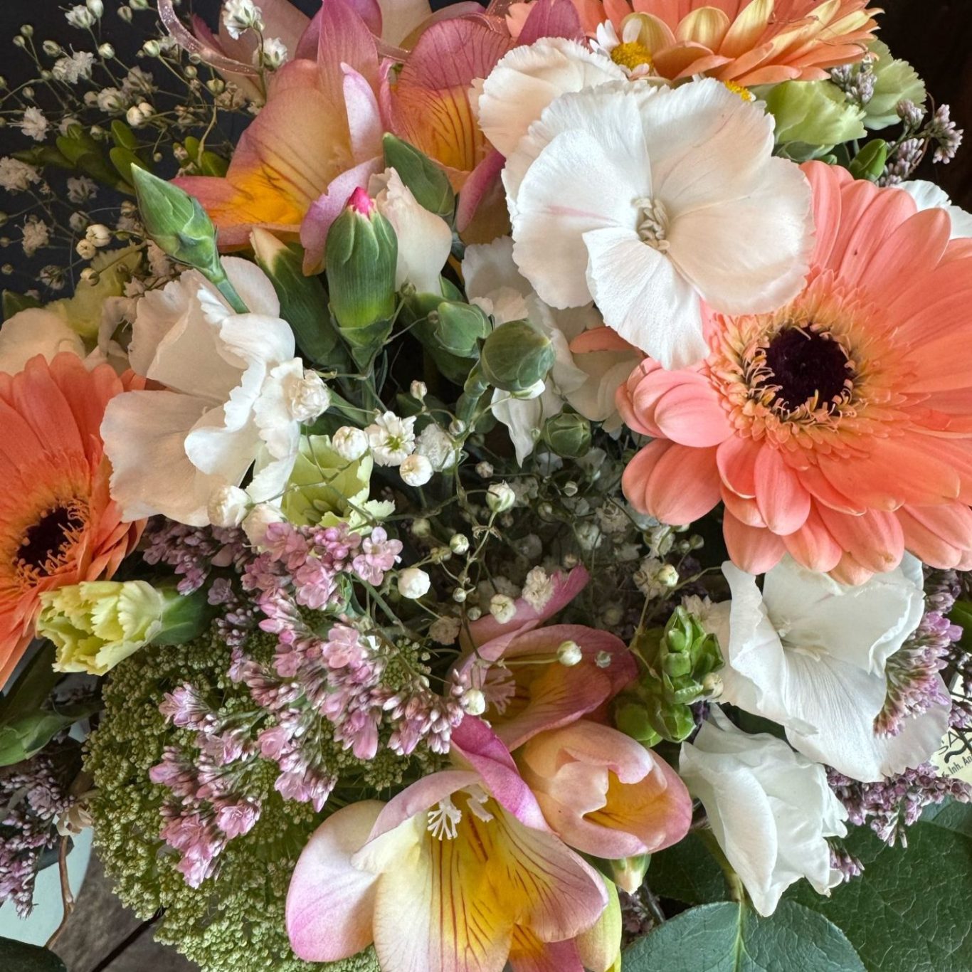 Bunte Blumenarrangement mit Gerbera, Rosen und verschiedenen Blüten in Weiß und Pastellfarben.